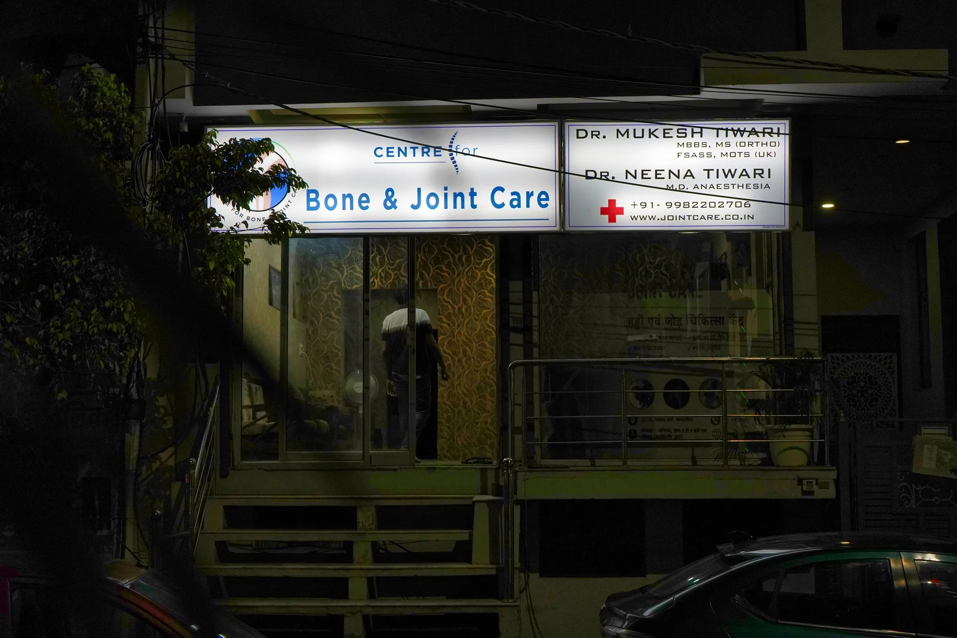 Closer night view of the illuminated Bone and Joint Care and doctors' signboards above the entrance